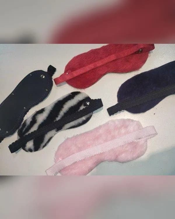 Varios antifaces ciegos forrados en peluche —rojo, violeta, rosa, cebra y uno de eco cuero negro—, cada uno con su elástico.