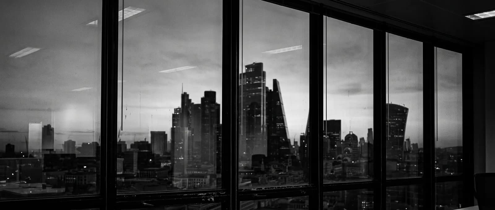 Skyline de un distrito financiero al atardecer visto a través del ventanal de una oficina en altura